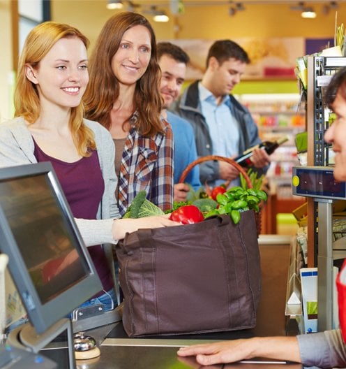 Group of shoppers waiting to pay for their groceries while using reusable bags 