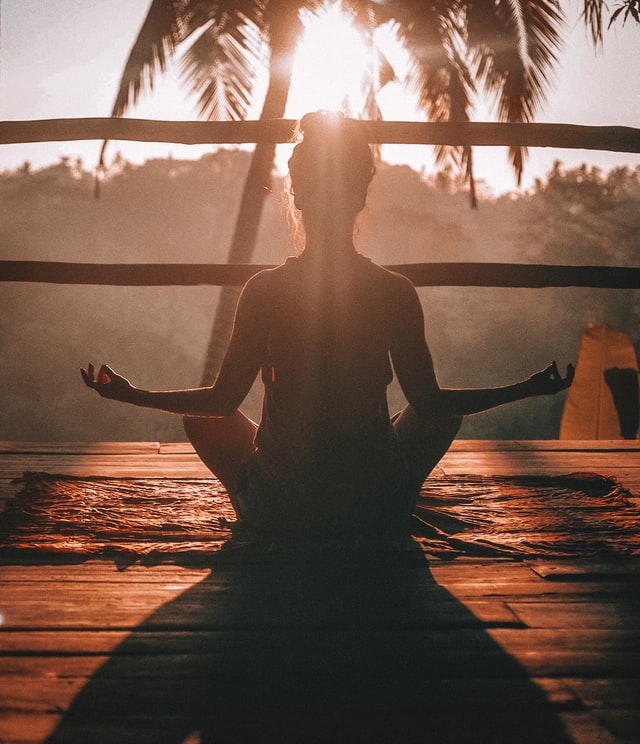 A woman meditating during sunset